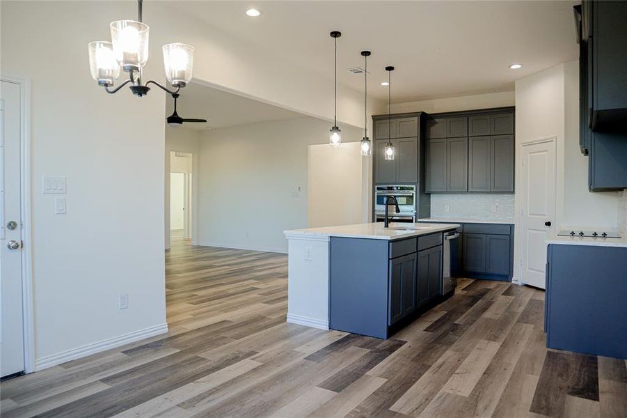 Kitchen featuring a center island with sink, hardwood / wood-style flooring, and hanging light fixtures