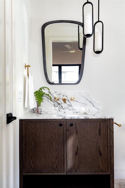 Calacatta marble, a bespoke brass faucet and the natural veining of white oak give the guest bath a bit of drama.