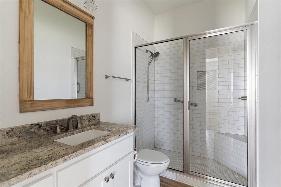 Bathroom featuring a shower with shower door, vanity, and toilet