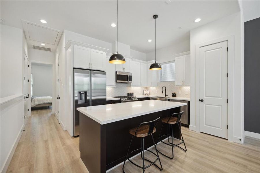 Large unobstructed kitchen island offers the perfect sitting area, and a vast amount of storage space. A sleek stainless steel farmer's sink and dark plumbing hardware complete the space.