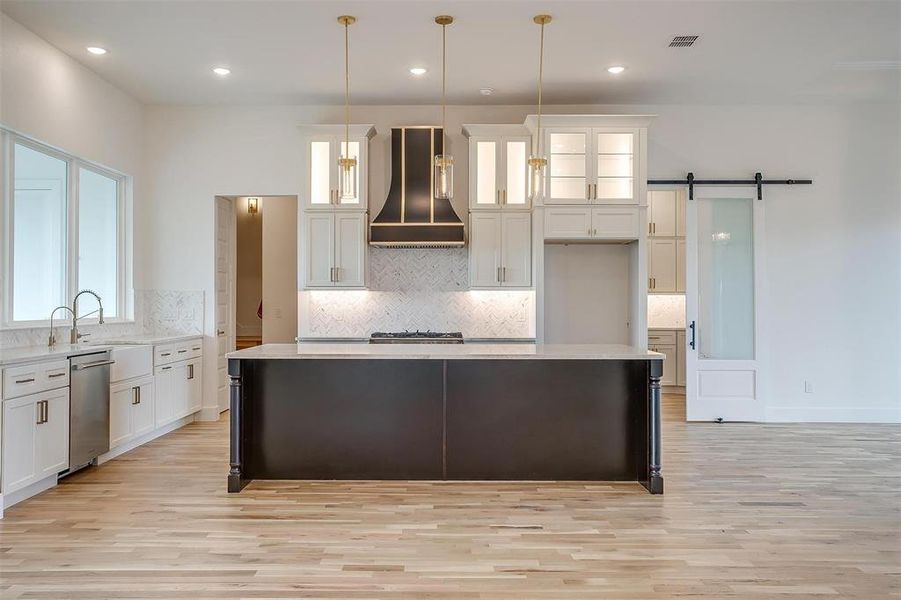 Kitchen with stainless steel dishwasher, a barn door, a center island, and wall chimney exhaust hood