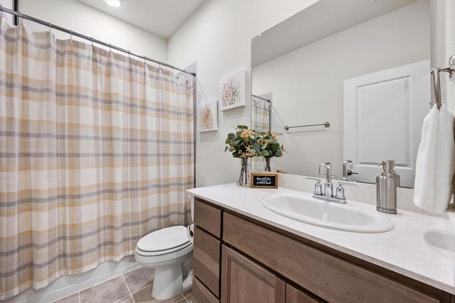 Full bathroom with tile patterned flooring, vanity, toilet, and shower / bathtub combination with curtain