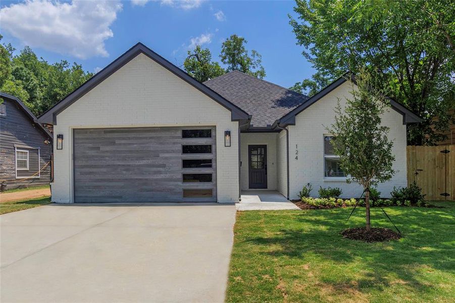 View of front facade featuring a garage and a front lawn