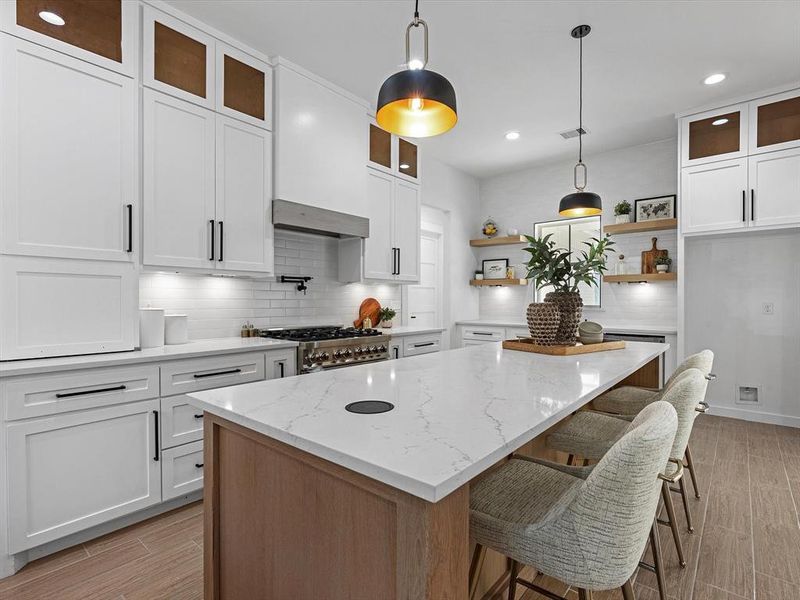 This kitchen is equipped with custom cabinets complemented by black hardware that coordinates beautifully with two pendant lights. It also includes timeless backsplash, a convenient pot filler, a specialized bread cabinet, high-quality ZLine appliances, and floor-to-ceiling cabinets for ample storage space. (fridge not included)