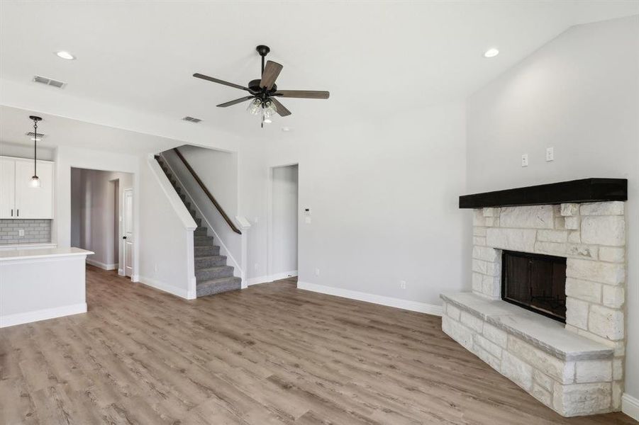 Unfurnished living room featuring a fireplace, ceiling fan, and wood-type flooring