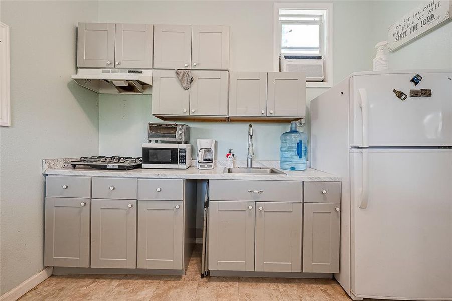 The kitchen features a refrigerator, a sleek microwave, and sink, combining modern functionality with stylish design.