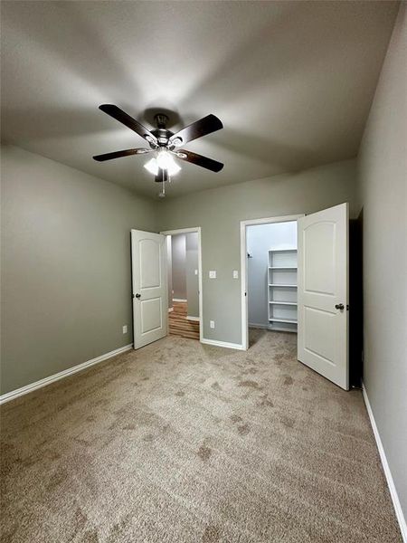 Unfurnished bedroom with carpet, ceiling fan, a walk in closet, and a closet