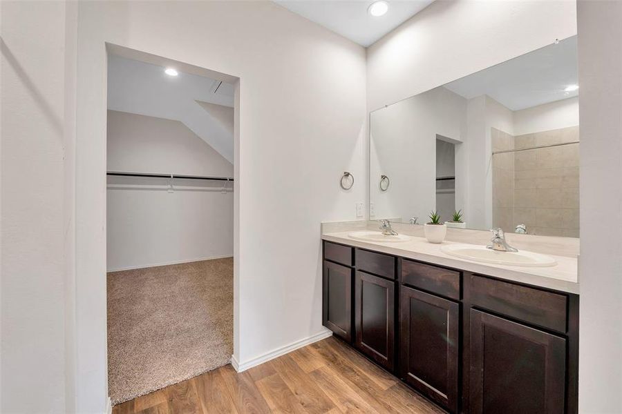 The primary bath features two sinks, a shower, plenty of under sink storage, and a closet.