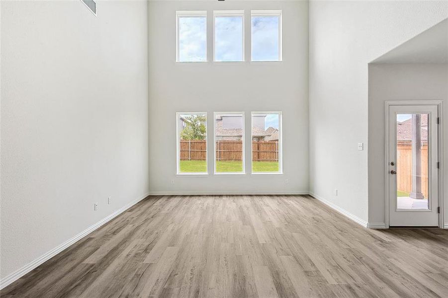 Unfurnished living room with a high ceiling and light hardwood / wood-style floors