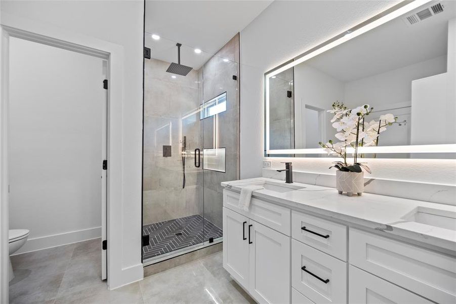 Bathroom featuring walk in shower, vanity, and toilet