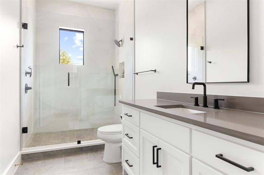 Bathroom featuring tile patterned floors, walk in shower, vanity, and toilet