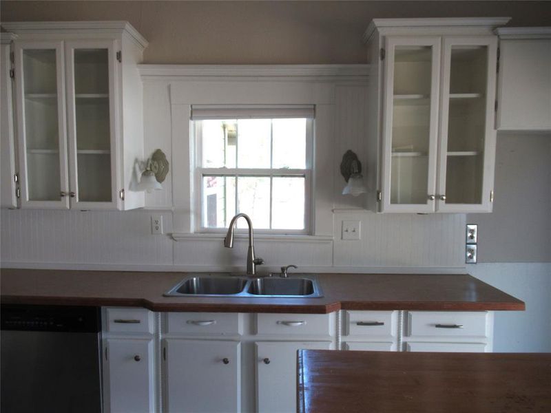 Kitchen with dishwasher, white cabinets, and sink