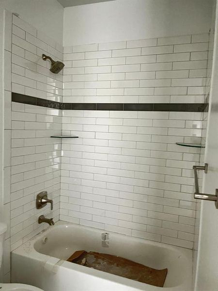 Bathroom featuring tiled shower / bath and toilet