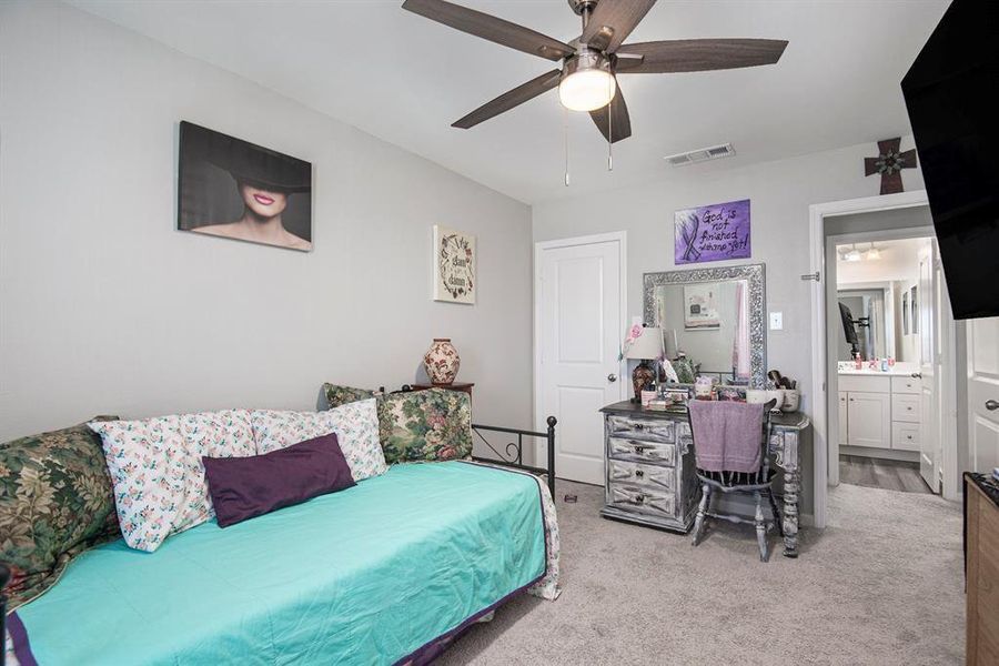 Carpeted bedroom featuring ceiling fan and connected bathroom