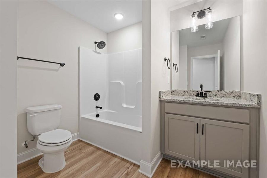 Full bathroom with vanity, toilet, hardwood / wood-style flooring, and shower / tub combination