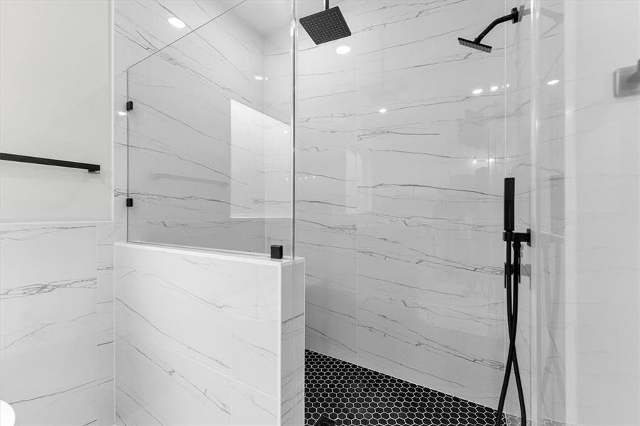 Large glassed front, walk-in shower with bench and three shower heads: rain head shower, wall shower, and handheld shower