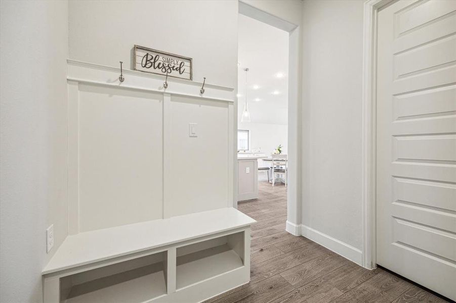 The custom built-in hall tree by the double car garage entry  is a practical and stylish addition to the home. It offers a designated space for storing coats, purses, and backpacks, helping to keep the area organized and clutter-free.
