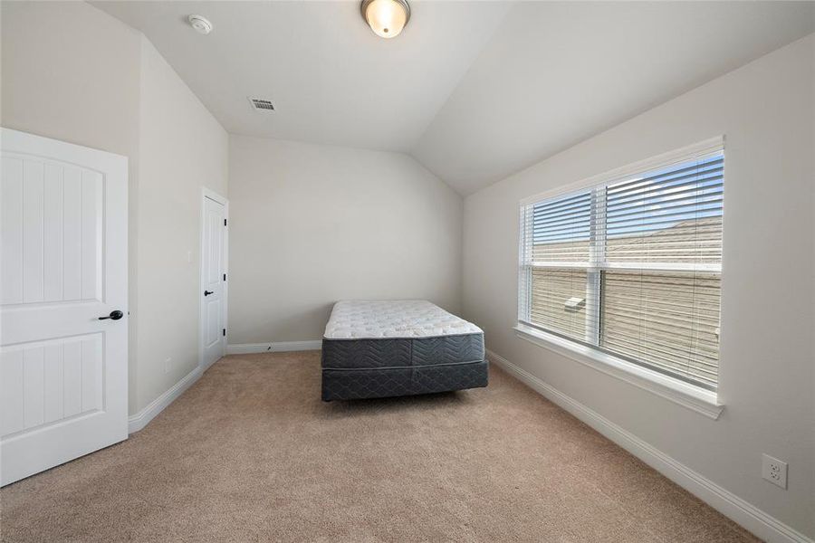 Bedroom with light colored carpet and vaulted ceiling