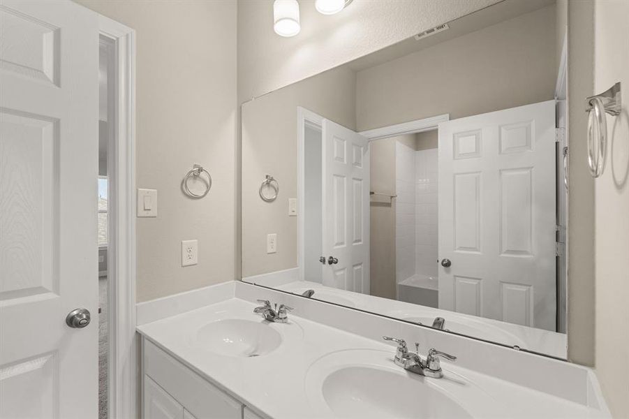 The secondary bath features tile flooring, white cabinetry and light countertops and a shower/tub combo. Perfect for accommodating any visiting family and friends.