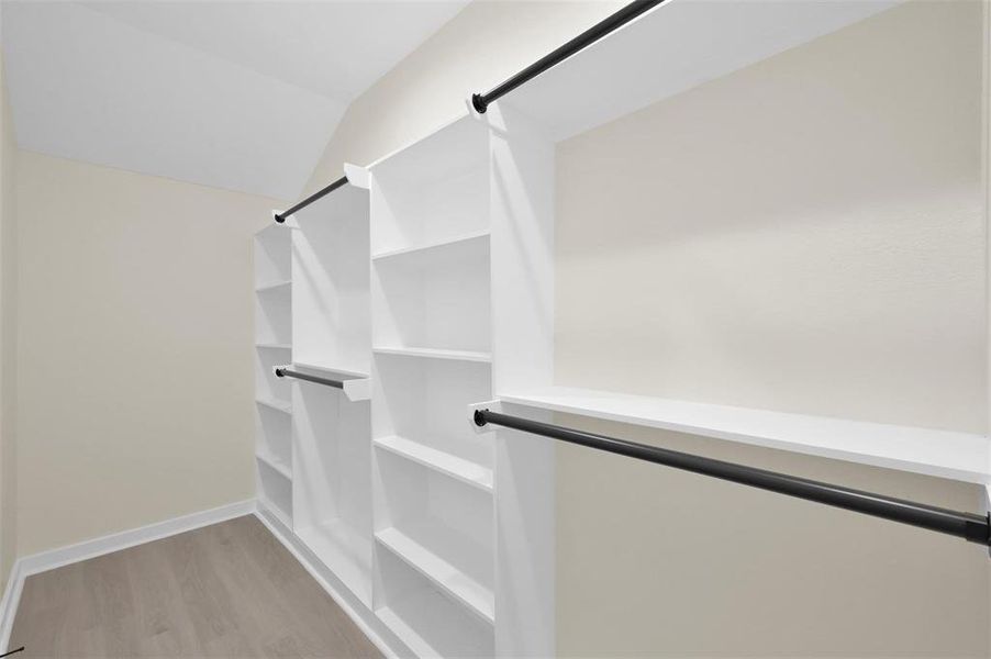 Primary closet with plenty of hanging space and storage shelves.