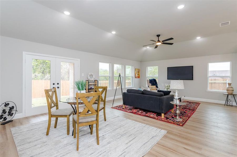 Dining room featuring vaulted ceiling, ceiling fan, light wood-type flooring, and plenty of natural light