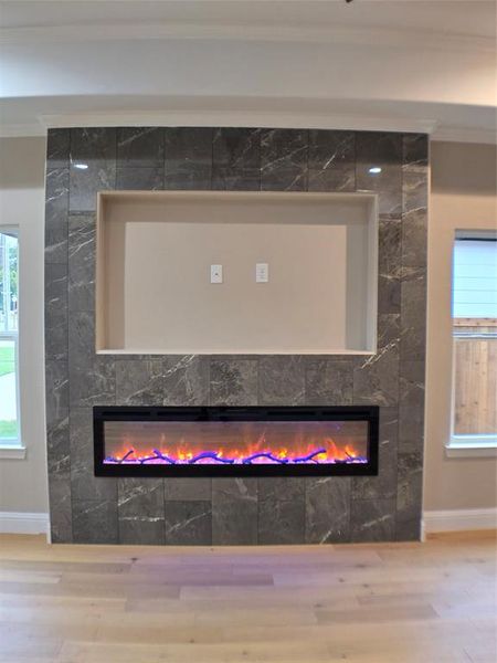 Interior details featuring wood-type flooring, a fireplace, and crown molding