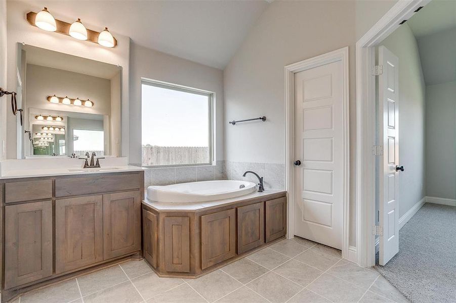 Bathroom with vanity, tile patterned flooring, a washtub, and vaulted ceiling