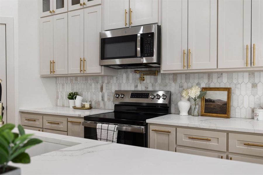 Kitchen with light stone countertops, stainless steel appliances, decorative backsplash, and white cabinetry