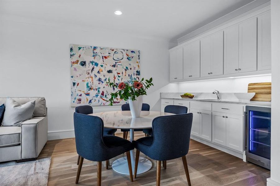 Dining space with beverage cooler, sink, hardwood / wood-style flooring, and ornamental molding