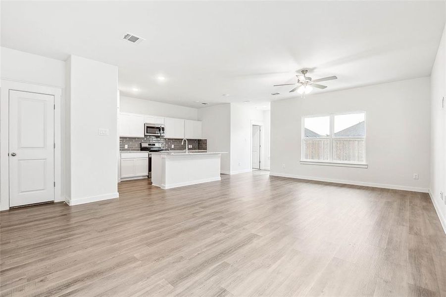 Unfurnished living room with ceiling fan, sink, and light hardwood / wood-style flooring