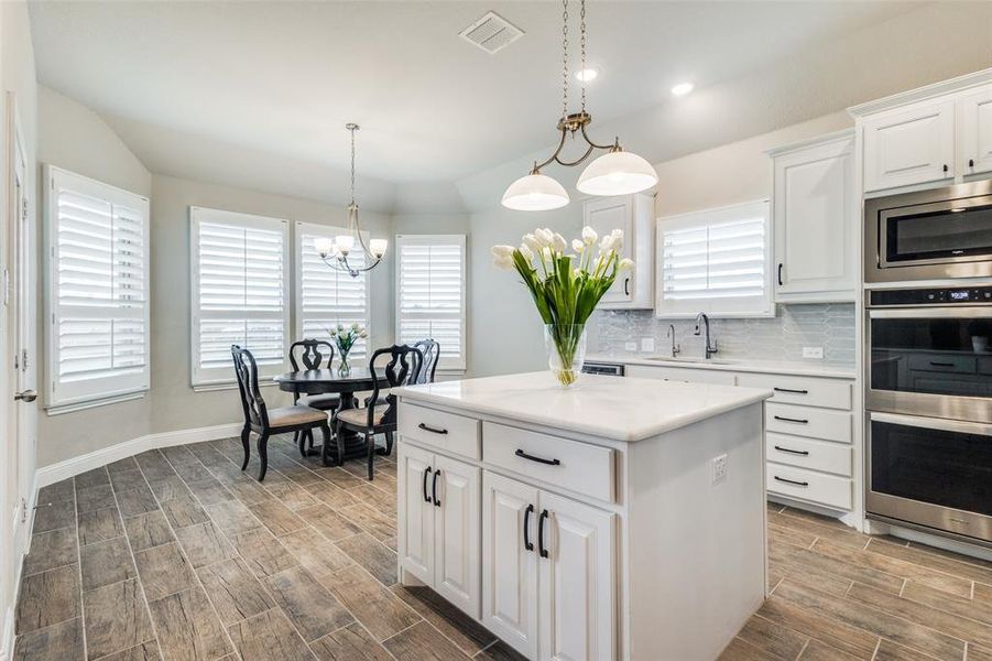 Kitchen with white cabinetry, tasteful backsplash, pendant lighting, sink, and appliances with stainless steel finishes