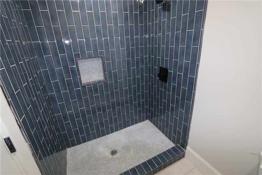 Bathroom featuring tile flooring and a tile shower