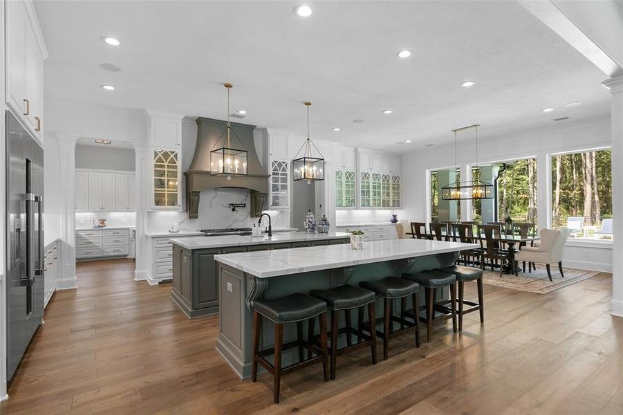 The kitchen is impeccably designed. Two islands, gorgeous Quartz counters, exquisite light fixtures, engineered wood floors, and plenty of glass front and traditional custom cabinets for storage.