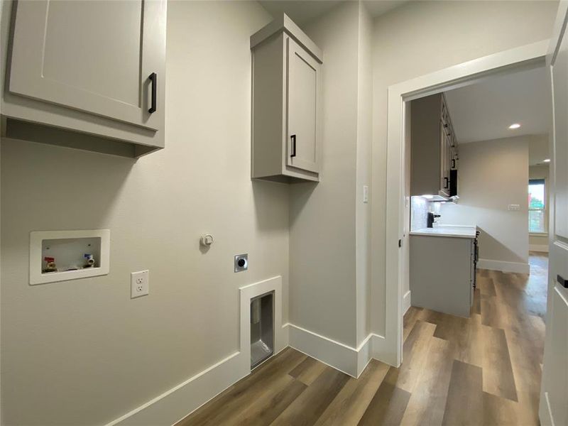 Clothes washing area with washer hookup, cabinets, hardwood / wood-style flooring, and electric dryer hookup