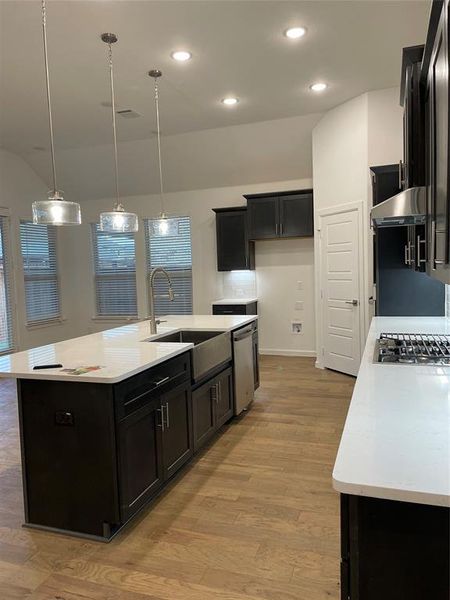 Beautiful open concept kitchen featuring stainless steel farm sink, lovely backsplash, and a large island with pendant lighting