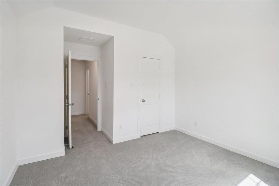 Unfurnished bedroom with lofted ceiling, a closet, and carpet flooring