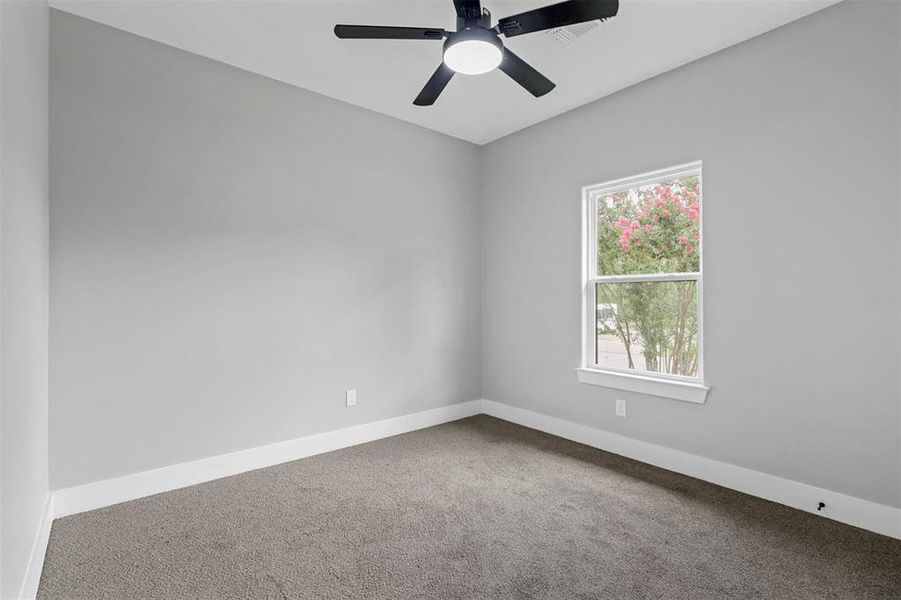 Carpeted empty room with a healthy amount of sunlight and ceiling fan