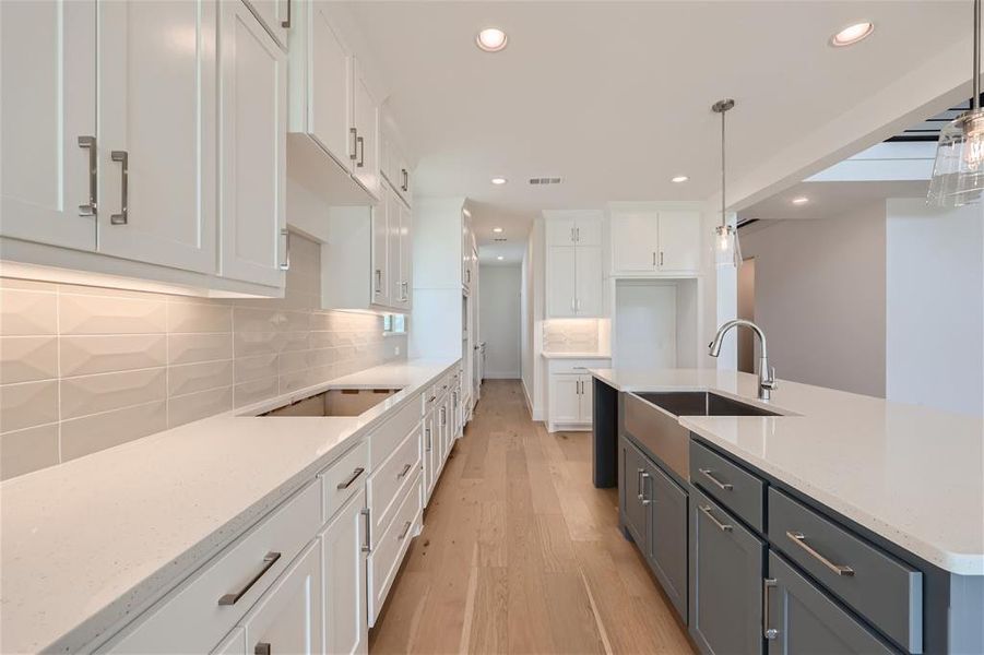 Kitchen with white cabinetry, tasteful backsplash, light hardwood / wood-style flooring, and pendant lighting