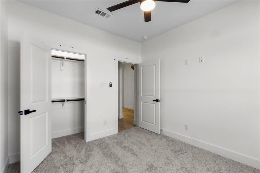 Unfurnished bedroom with ceiling fan, a closet, and light colored carpet