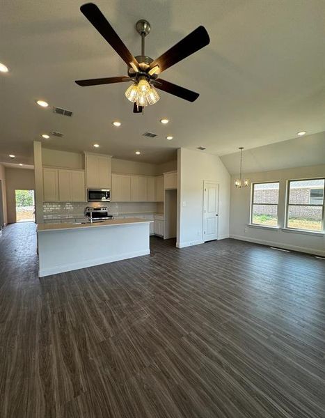 Kitchen featuring white cabinetry, appliances with stainless steel finishes, ceiling fan with notable chandelier, vaulted ceiling, and dark hardwood / wood-style flooring