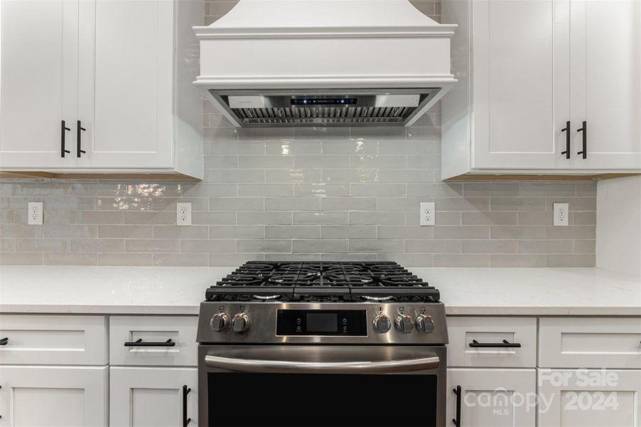 Look at that custom range hood atop a fantastic gas stove with electric oven.