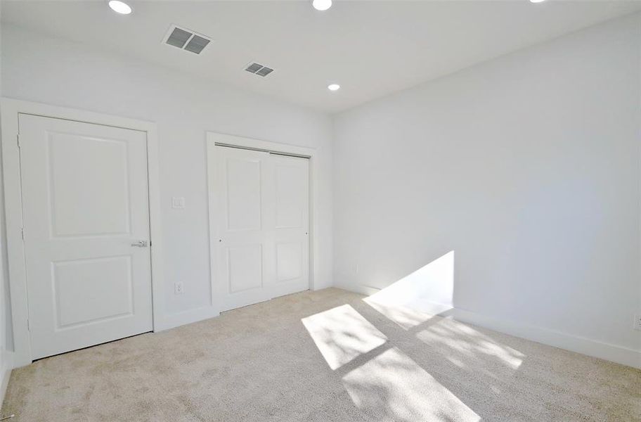 Unfurnished bedroom featuring light carpet and a closet