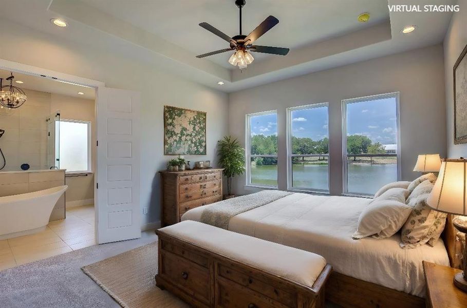 Bedroom featuring a water view, a tray ceiling, ceiling fan with notable chandelier, and light tile patterned floors