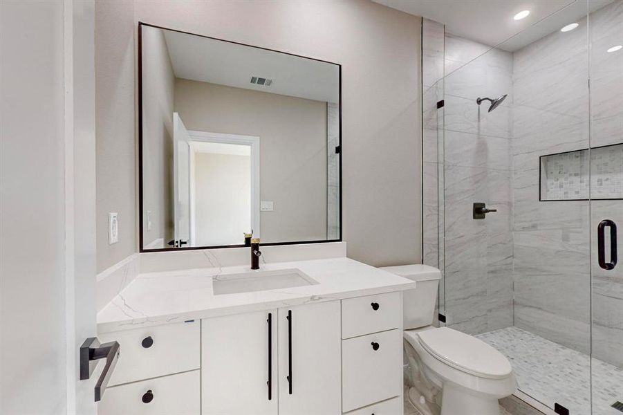 Bathroom with a shower with door, vanity, and toilet