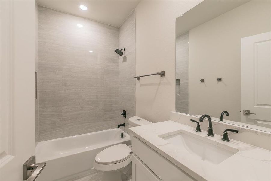 Full secondary bathroom with vanity, tiled shower / bath combo, and toilet