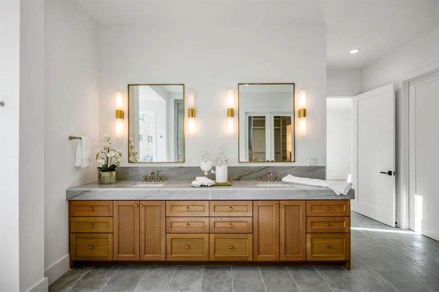 A classic European touch with dual vanities, sconce wall lighting, and solid natural wood cabinets. Closed door to the right is one of two walk-in closets.