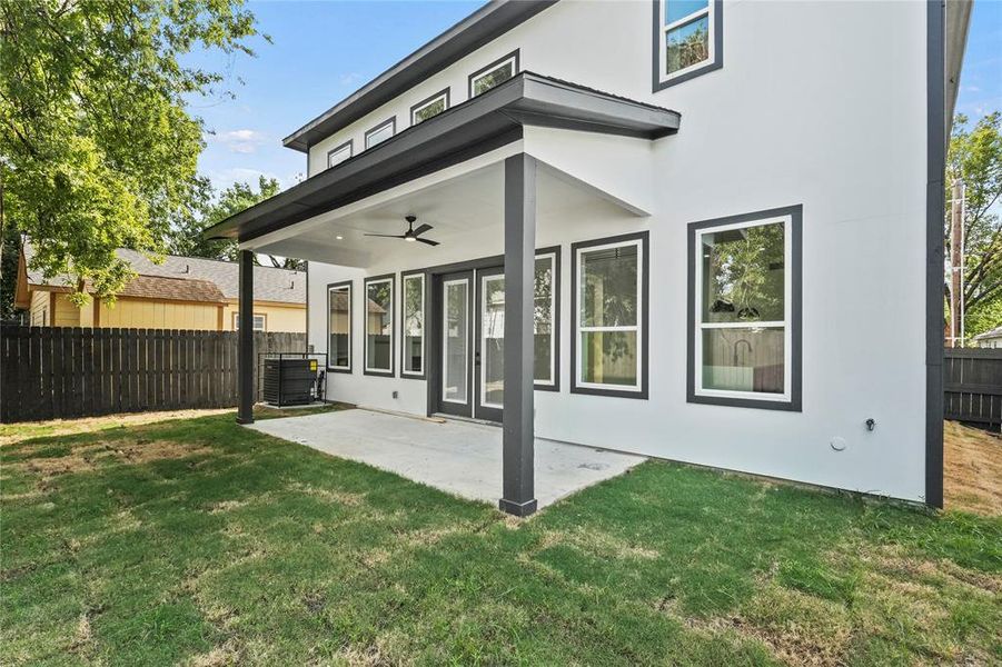 Rear view of house with central air condition unit, ceiling fan, a lawn, and a patio area