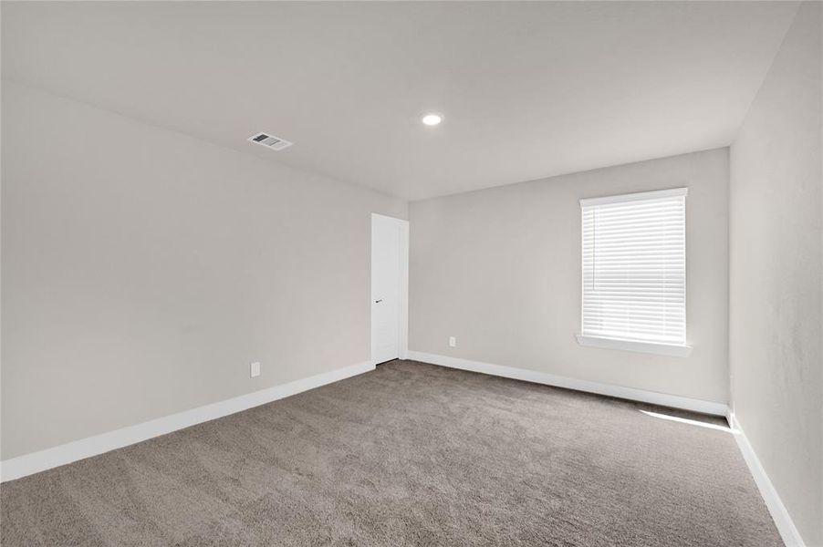 This secondary bedroom is located on the second floor featuring plush carpeting, neutral paint, walk-in closet, and natural lighting through a large double pane window.