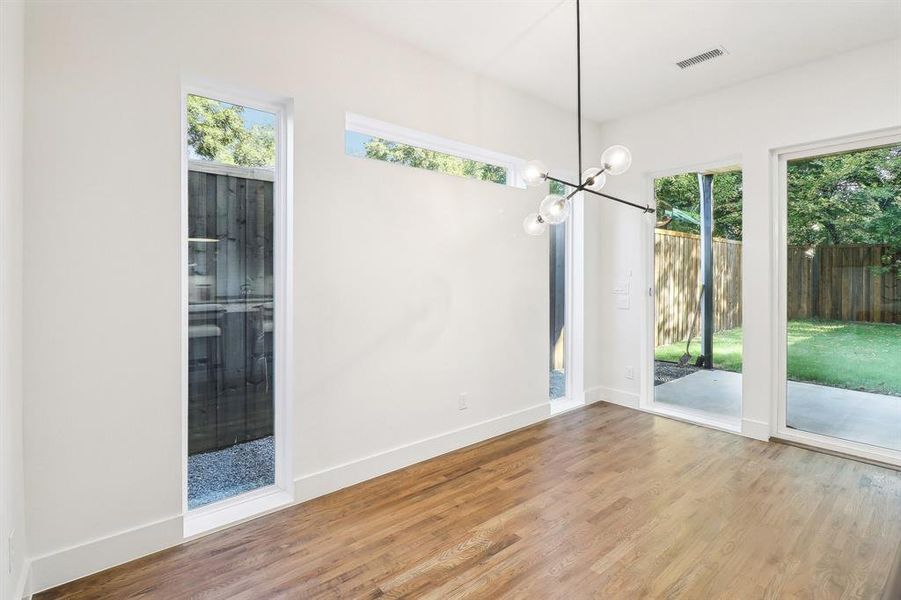 Unfurnished dining area featuring a wealth of natural light, an inviting chandelier, and light hardwood / wood-style floors