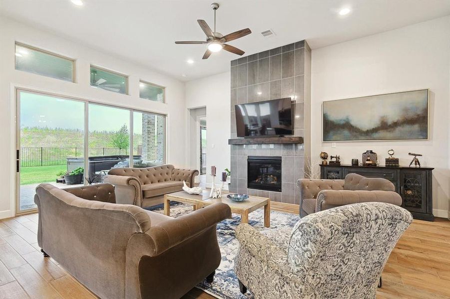 Living room with light hardwood / wood-style flooring, ceiling fan, and a tile fireplace